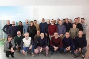 group of men and women posing in an office setting smiling