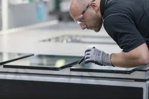 man in a lab setting leaning over 2 glass units and inspecting them