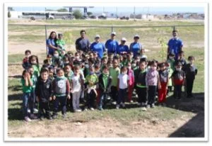 group of people posing outside with children in a community school area