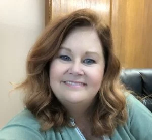 smiling woman with red wavy hair and a green shirt portrait, head shot